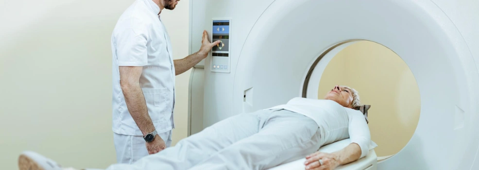 Patient lying inside an MRI scanner while a technician prepares the imaging procedure.