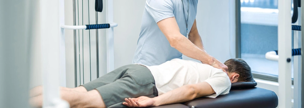 Physiotherapist performing manual back treatment on a patient lying face down on a clinic table.